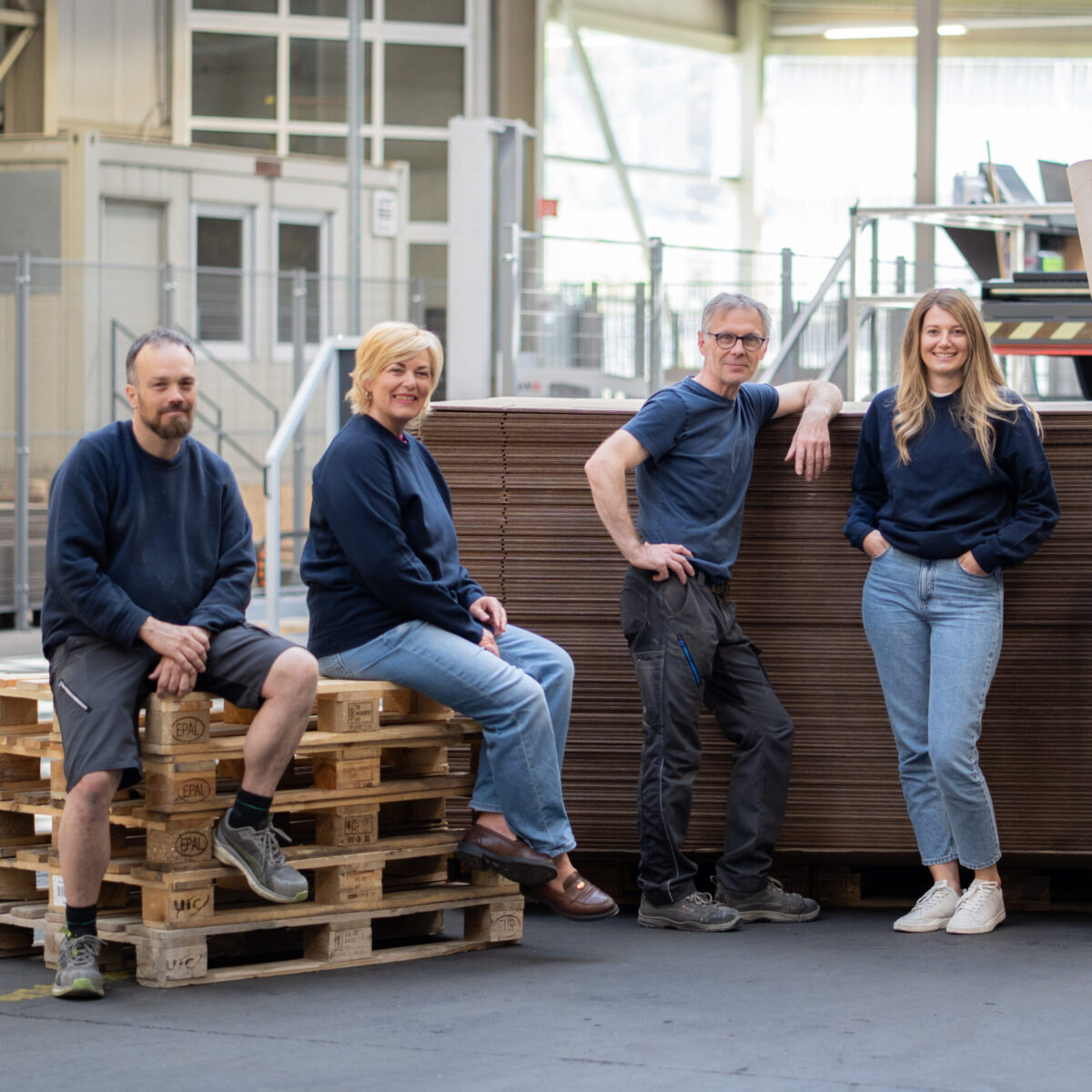 Fünf Mitarbeiter bei pratopac in der Produktionshalle mit ihren Produkten aus Karton.