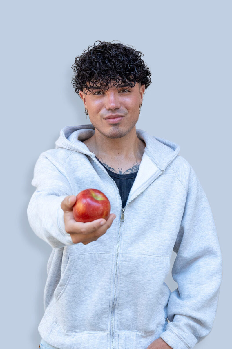 Portrait von Martin, der einen Apfel in der Hand hält, damit symbolisiert er sein Interesse an gesunder Ernährung.